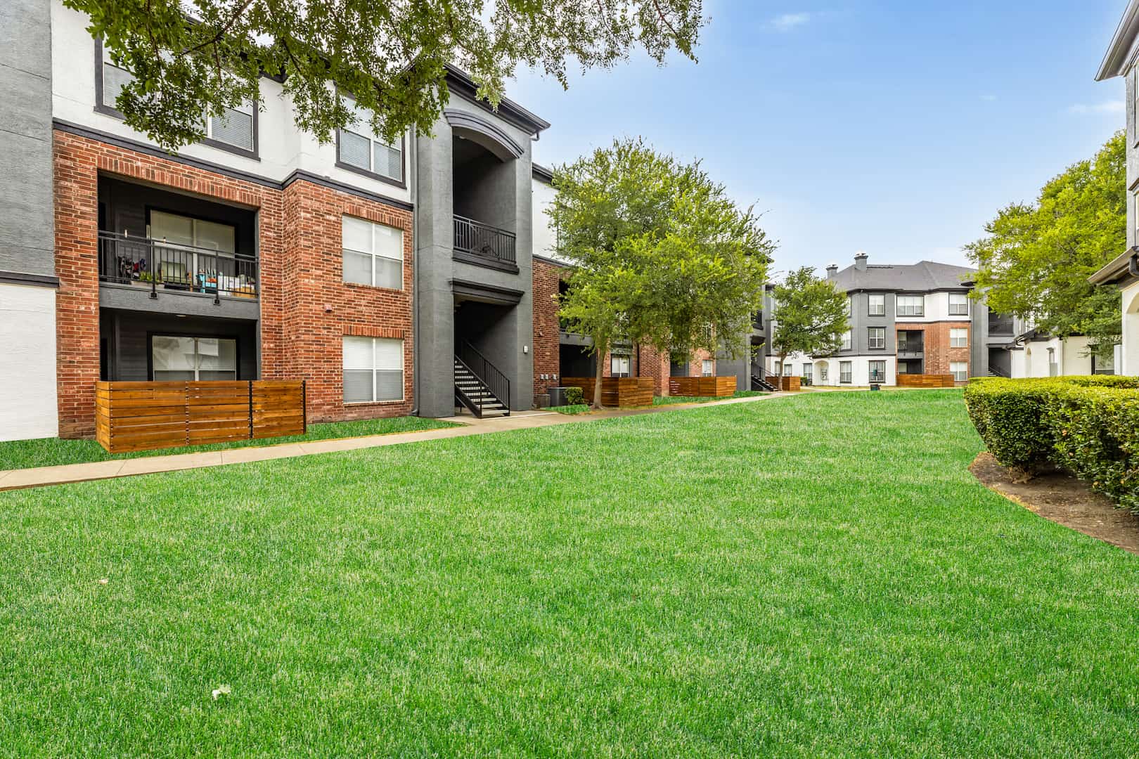 green grassy areas with trees surrounding apartments